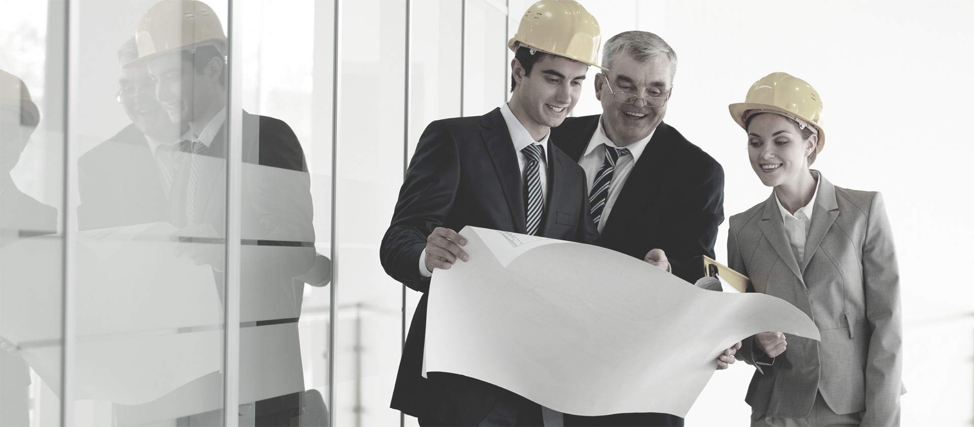 3 people looking a building plans, 2 of them wearing hardhats